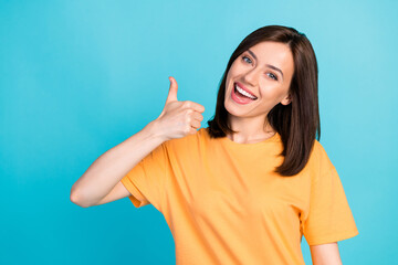 Sticker - Portrait of glad pleasant cute woman with long hairstyle dressed yellow t-shirt showing thumb up isolated on blue color background