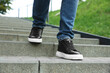 © New Africa - Man in stylish black sneakers walking down stairs, closeup