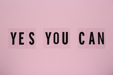 phrase yes you can of plastic letters on pink background, top view. motivational quote