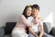 © bennnn - Laughing and hugging asian brother and sister with care and love on sofa at home.