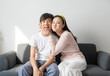Laughing and hugging asian brother and sister with care and love on sofa at home.