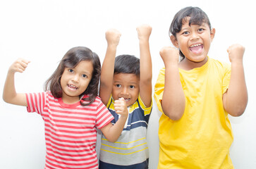 Multi racial of asian little kids showing expression of happines and over joy with hand fist raising showing strength and growth