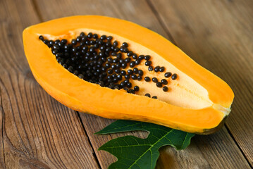 Wall Mural - fresh ripe papaya tropical fruit with papaya seed and leaf leaves from papaya tree, papaya fruits on wooden background