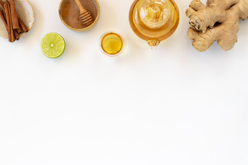 Wall Mural - Top view of a cup of tea with ginger root, lime, cinnamon and teapot on white background. Health drink concept..