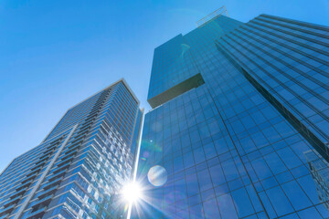 modern glass residential buildings towering against sun and blue sky background