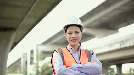 Wall Mural - Confident woman Engineer or architect looking camera with white safety helmet in construction site. Supervisor Engineer female working at construction project. Civil engineering concept.