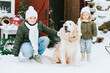 © klavdiyav - siblings girl sister and teenage cute boy brother in knitted sweater and hat having fun with first snow and cute pet dog labrador at porch of country house, concept of winter spirit and Christmas