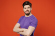 © ViDi Studio - Side view young brunet caucasian man 30s in casual basic purple t-shirt look camera hold hands crossed folded look camera isolated on plain orange background studio portrait. People lifestyle concept.