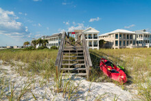 Destin, Florida- Red Kayak Boat Beside The Stairs Of A Footbridge Over The Sand Dunes