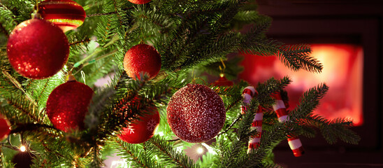 Wall Mural - Christmas tree decoration and lights close up view, burning fireplace background.