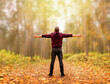 © Anastasiia - A relaxed adult man is standing on a path in the autumn forest, breathing fresh air. The arms are spread apart