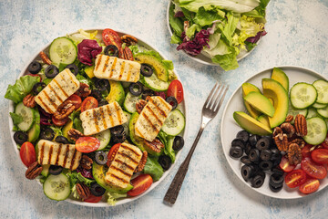 Wall Mural - Greek style cuisine - salad with grilled halloumi cheese, avocado, pecan nuts and tomatoes.