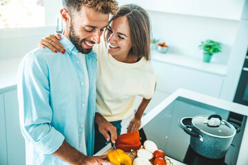 Young happy couple preparing healthy meal in kitchen at home