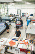 © guruXOX - In a large modern printing plant, operators work on various types of machines for printed material