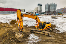 A Powerful Excavator Digs The Earth In Northern Conditions. Heavy Construction Machinery In Winter Conditions. Shooting From A Drone. Close-up. Excavation With An Excavator In The North.