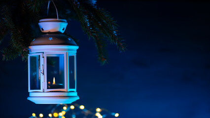 Sticker - Christmas lantern is hanging on a Christmas tree branch on a blue background . holiday banner with copy space