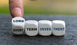 Hand turns dice and changes the expression 'short term investment' to 'long term investment'.