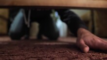 Man Looking For Something Under The Bed. The Hand Gropes For An Object