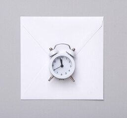 White Envelope with alarm clock on a gray background.
