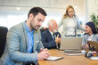 © Bojan - Handsome young business man writing notes on a clipboard in office.