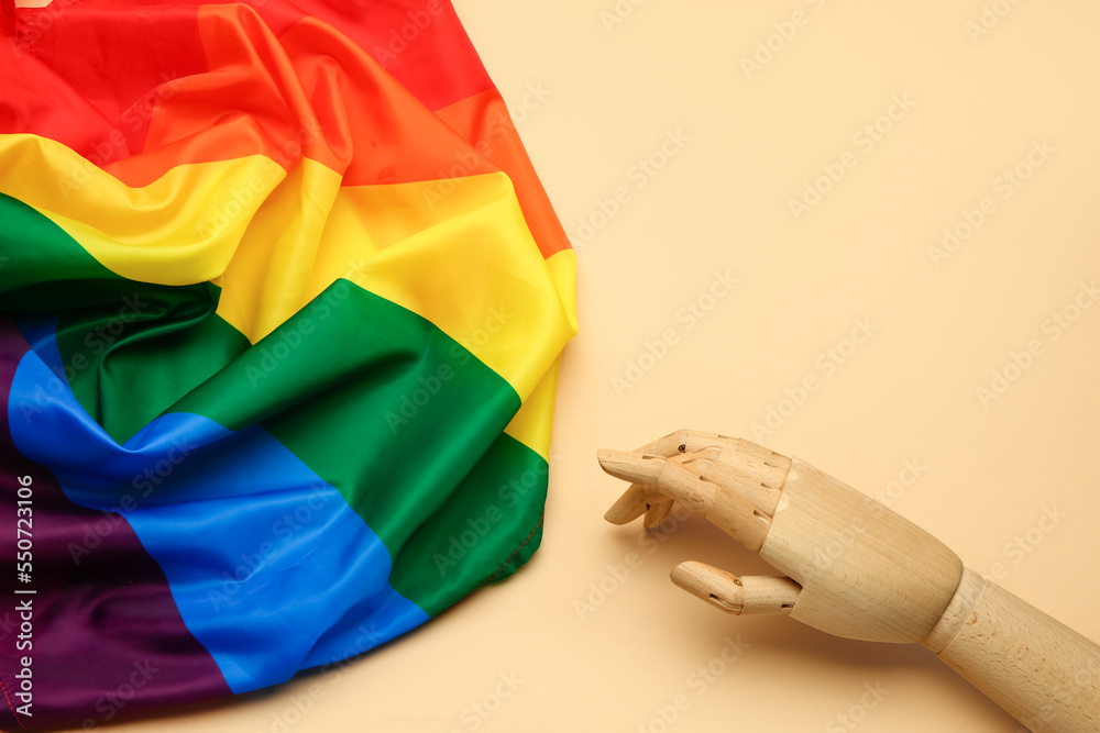 Wooden hand with LGBT flag on beige background