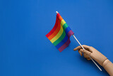 Fototapeta Tęcza - Wooden hand with LGBT flag on blue background