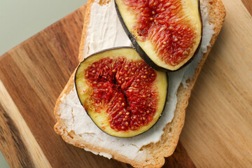 Wooden board of tasty bruschetta with cream cheese and figs, closeup