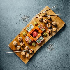 Wall Mural - Closeup of delicious sushi set on a wooden board on a gray table