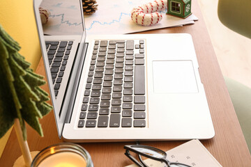 Laptop with Christmas toys on table in office, closeup