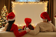 Leinwandbild Motiv Family watching movie on projection screen in room decorated for Christmas, back view. Home TV equipment