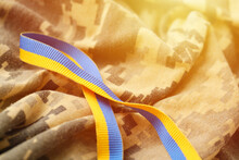 Pixeled Digital Military Camouflage Fabric With Ribbon In Blue And Yellow Colors. Attributes Of Ukrainian Patriotic Soldier Uniform