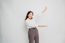 Excited Asian Woman Wearing White Shirt Pointing At The Copy Space Beside Her, Isolated By White Background