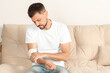 © New Africa - Man with arm wrapped in medical bandage on sofa indoors