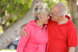 coppia di anziani con abiti sportivi molto sgargianti  si abbraccia felice in un parco