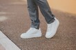 © Omar Tursić/Wirestock Creators - Close-up shot of a man wearing white sneakers with gray classic pants