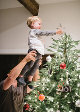 Young Boy Placing Christmas Star On Tree