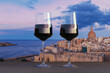 Two wine glasses with view of sunset over Valletta old town and harbor, Valletta, Malta.