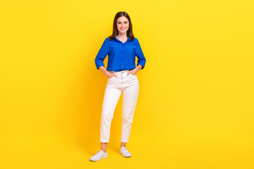 Wall Mural - Full length photo of adorable charming girl dressed blue shirt standing arms pockets isolated yellow color background