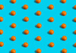 Summer flat lay pattern made with fresh orange fruit on teal blue background. Minimal concept with soft shadows.