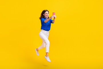 Sticker - Full length photo of excited pretty lady wear blue shirt jumping high recording video vlog device isolated yellow color background