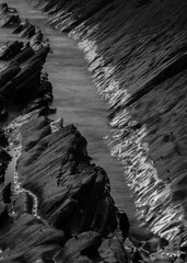 Wall Mural - Abstract landscape picture of rocks on Welcome Mouth Beach at sunset with tide marks on rocks reflecting sunlight