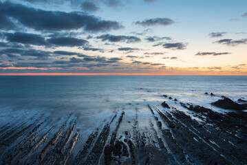 Wall Mural - Beautiful sunset landscape image of Welcome Mouth Beach in Devon England with beautiful rock formations