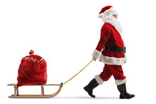 Full Length Profile Shot Of Santa Claus Pulling A Wooden Sled With A Red Sack Full Of Presents