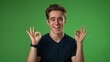 © Robert Peak - Portrait of young hipster man 20s giving okay gesture smiling happy isolated on green screen background studio portrait slow motion