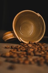 Poster - Vertical closeup of a flipped cup with coffee beans on the table dark background