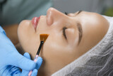 Fototapeta  - Cosmetologist applying chemical peel product on client's face in salon, closeup