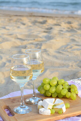 Wall Mural - Glasses with white wine and snacks for beach picnic on sandy seashore