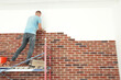 © New Africa - Professional builder gluing decorative bricks on wall indoors. Tiles installation process