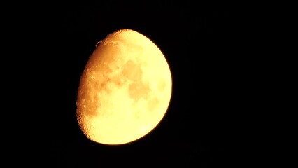 Wall Mural - Timelapse. A glowing golden huge moon as seen from earth through the atmosphere against a starry night sky. A large moon moves across the sky, the moon moving from the left frame to the right.