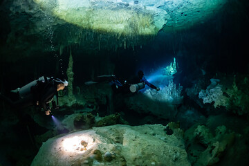 Wall Mural - cave diver instructor leading a group of divers in a mexican cenote underwater